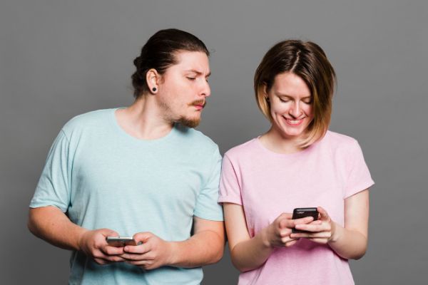 Homem olhando uma mulher mexendo no celular