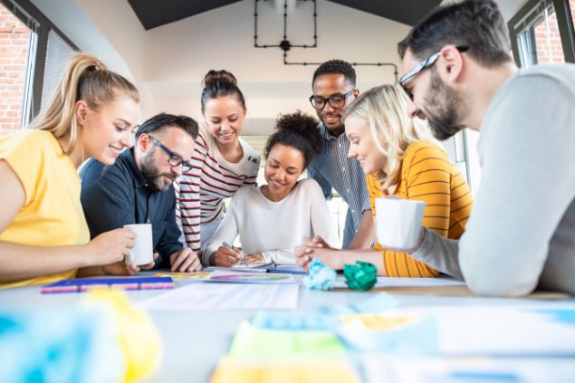Colegas de trabalho em volta de uma mesa, falando sobre algum projeto