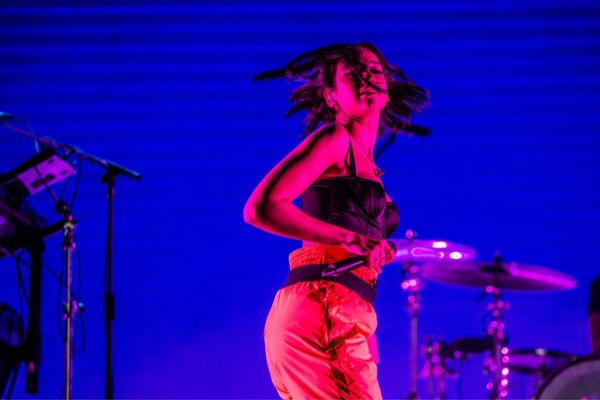 Dua Lipa segurando microfone e dançando durante show
