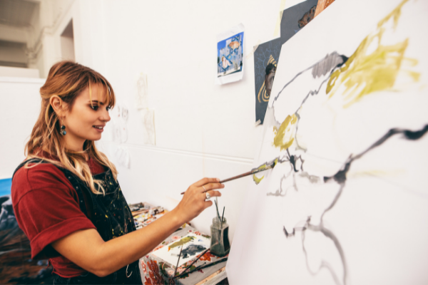 Mulher sorrindo e pintando um quadro