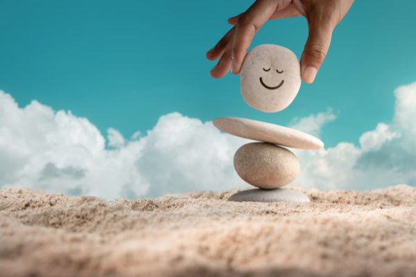 Pedrinhas equilibradas uma em cima da outra. A pedra do topo possui o desenho de um sorriso