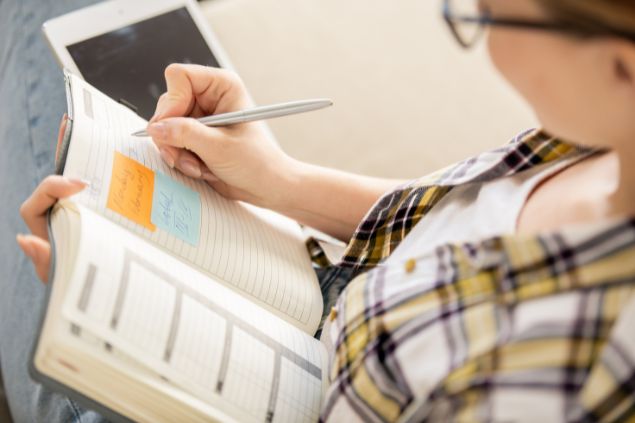 Mulher escrevendo seus objetivos em uma agenda