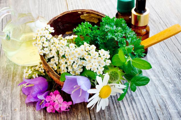 Imagem de flores de diversos tipos em uma tijela e ao lado conta-gotas e um jarro
