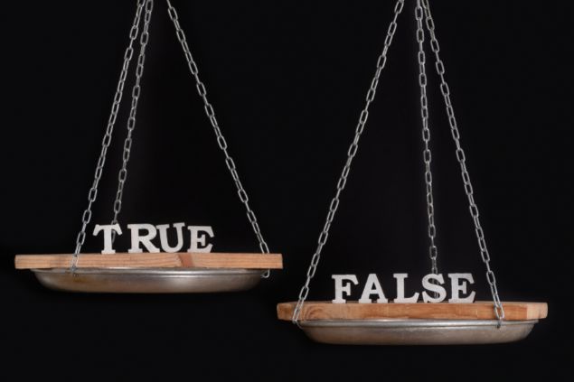 Imagem de uma balança e as palavras falso e verdadeiro em inglês cada uma em um lado da balança e a mais pesada é a palavra falso