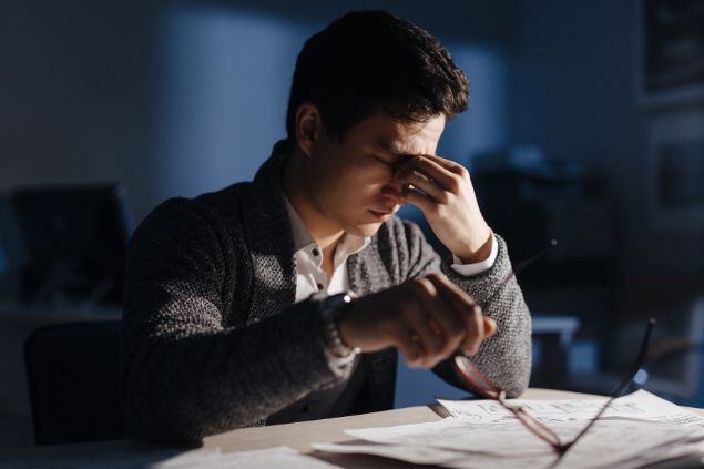 Imagem de um homem sobrecarregado com o trabalho e aperenta sentir dores de cabeça