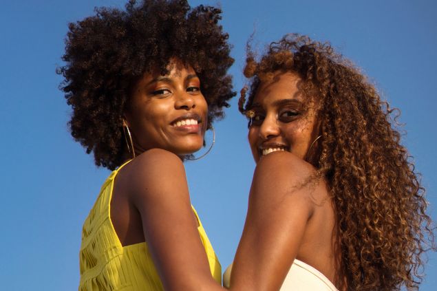 Imagem de um casal de mulheres abraçadas e sorrindo