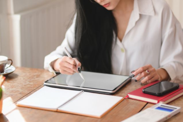 Mulher escrevendo em seu tablet em uma mesa de escritório