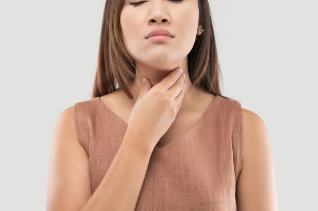 Mulher com os olhos fechados e com a mão no pescoço