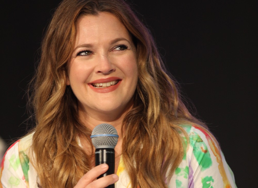 Atriz Drew Barrymore falando em um microfone durante evento na Austrália em 2019