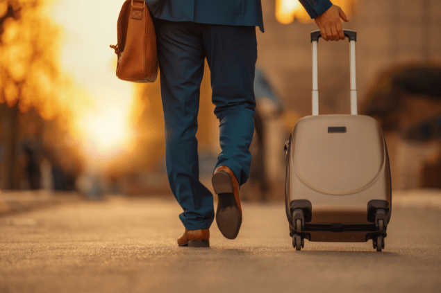 Homem caminhando com uma mala de rodinha na mão
