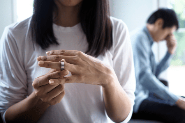 Casal enfretando problemas de relacionamentos. Mulher tira sua aliança do dedo.