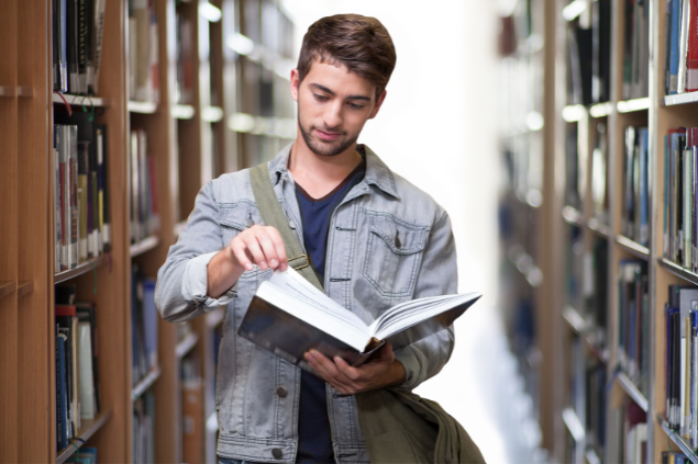 Homem lendo um livro em meio a uma biblioteca
