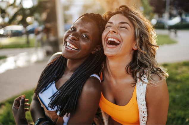 Duas mulheres sorrindo enquanto se abraçam