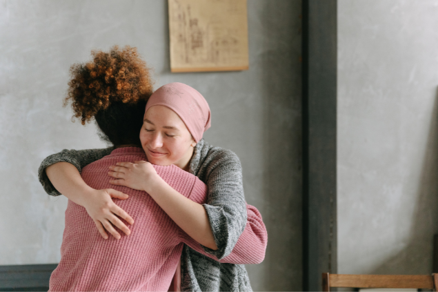 Duas mulheres se abraçando enquanto fecham os olhos