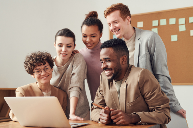 Cinco pessoas rindo enquanto olham para um notebook