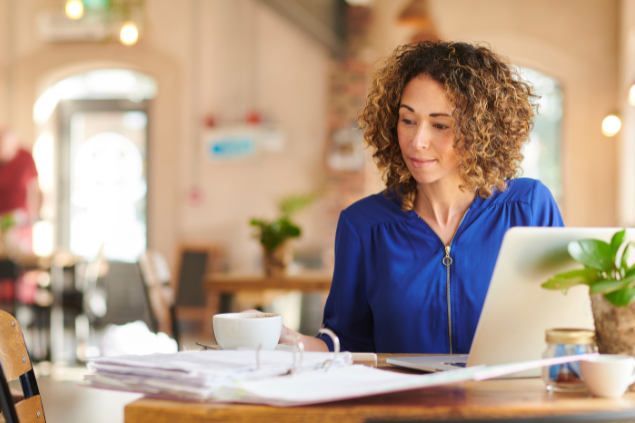 Mulher trabalhando enquanto toma um café