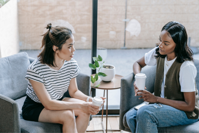 Duas mulheres sentadas tomando um café enquanto conversam