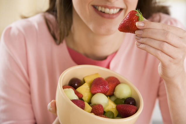 Mulher comendo tigela cheia de frutas