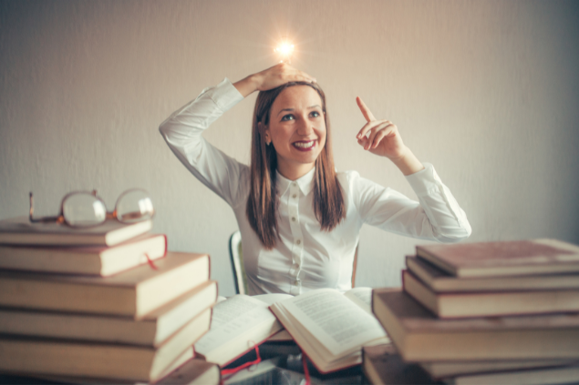 Mulher ao redor de livros e com uma lâmpada acesa na cabeça