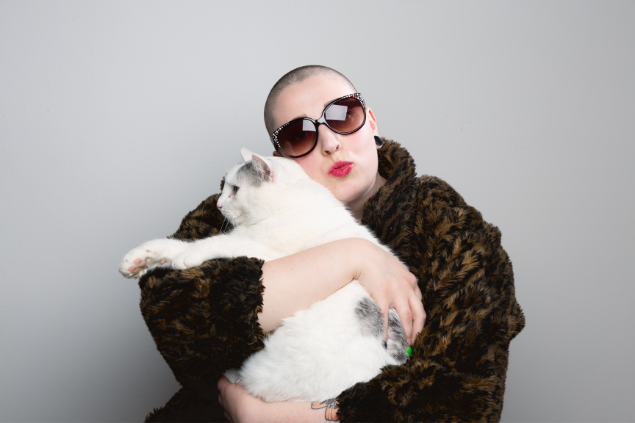 Mulher de cabeça raspada segurando um gato
