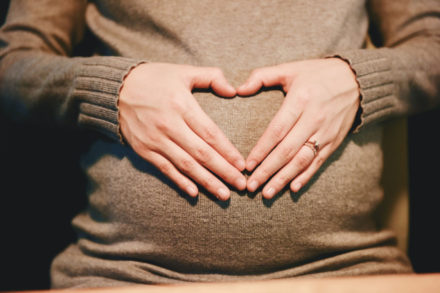 Mulher grávida fazendo coração na barriga