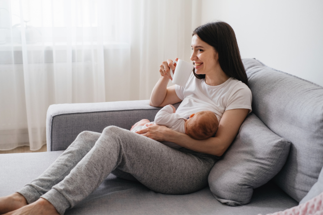Mulher amamentando bebê enquanto está sentada no sofá