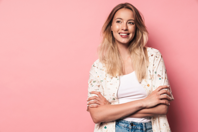 Mulher loira sorrindo de braços cruzados