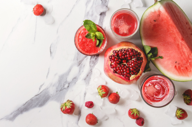 Frutas vermelhas em cima de uma mesa de mármore: melancia, morango, entre outras.
