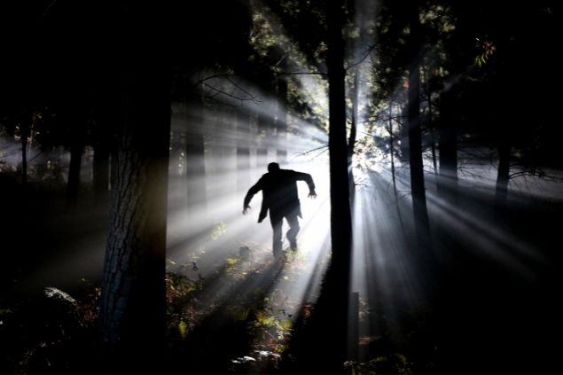 Imagem da silhueta de um homem andando em uma floresta no escuro, simbolizando o Exu do Lodo.