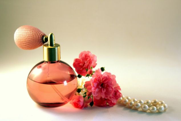 Imagem de um vidro de perfume, cravos na cor rosa e um colar, um dos exemplos de oferenda para as pombagiras.