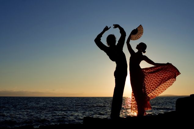 Imagem de um casal de ciganos dançando em um ritual da Umbanda no meio da praia. O homem, simboliza o cigano Pablo da Umbanda.