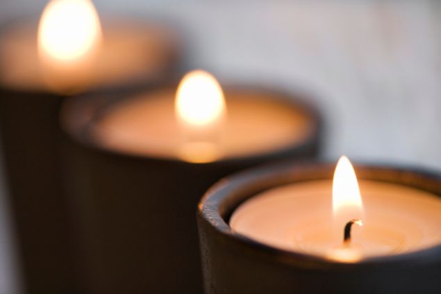 Imagem de três velas pretas acesas, simbolizando uma oferenda para o Exu da Morte.