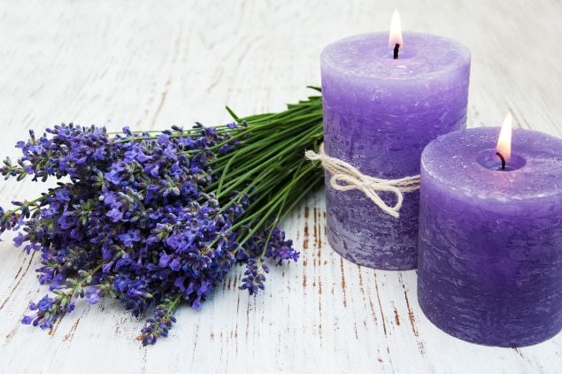 Imagem de duas velas na cor lilás e um arranjo floral de lavanda também na cor lilás, simbolizando uma das oferendas para a cigana Sara da Umbanda.