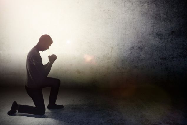 Imagem de um homem com uma das pernas de joelhos e a outra dobrada. Ele segue em oração.