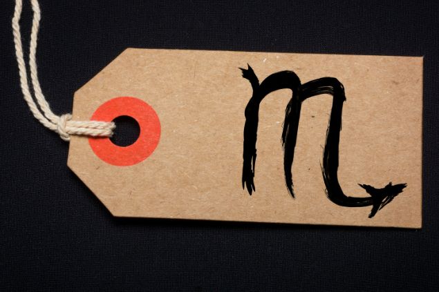 Imagem de fundo preto e em destaque uma etiqueta com o glifo de escorpião.