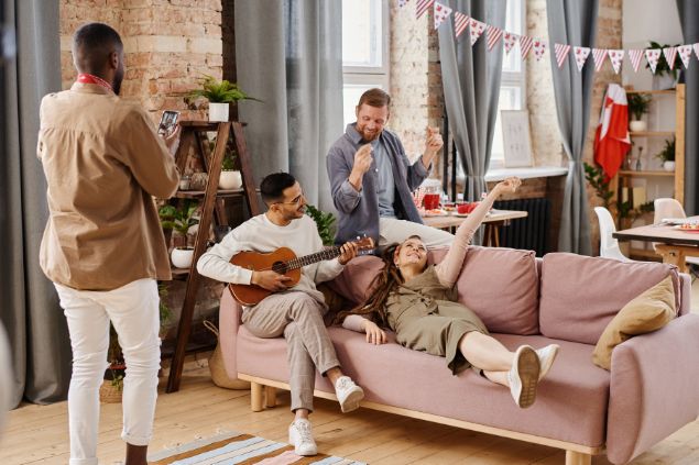 Imagem de pessoas reunidas em casa, se divertindo, tocando violão e cantando, representando o signo de aquário.