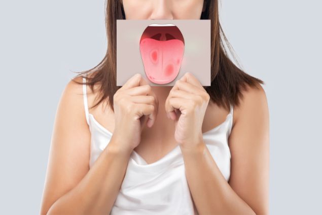 Imagem de uma mulher mostrando a língua para o seu acupunturista. Ela está com alguns problemas de saúde na língua.