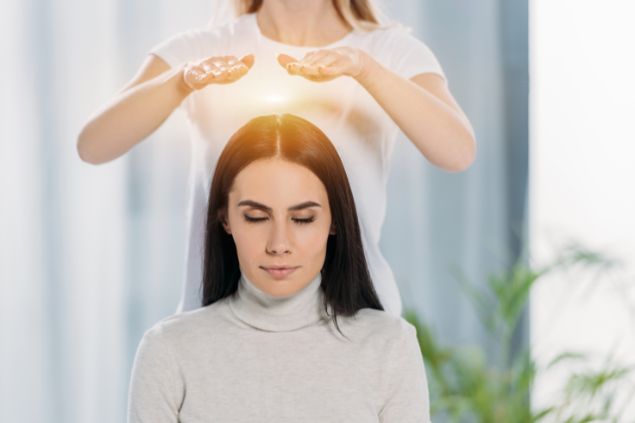 Imagem de uma terapeuta aplicando o reiki em uma paciente.