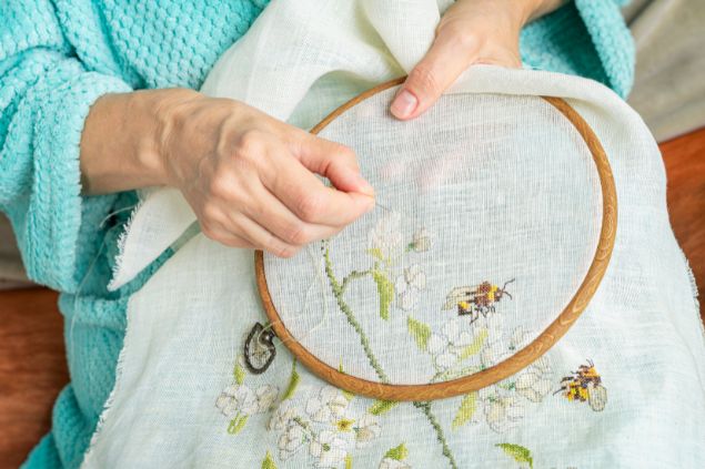 Imagem das mãos de uma mulher fazendo um bordado em um tecido, uma das habilidades do signo de touro.