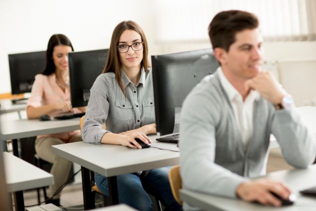 Imagem de alunos do signo de aquário em uma sala de aula informatizada.