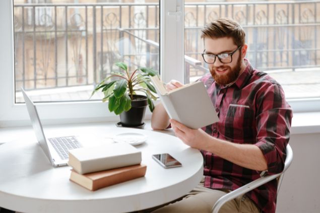 Imagem de um homem do signo de áries estudando. Ele está fazendo uma leitura em um livro   tudo muito rápido, o que compromete seu aprendizado.