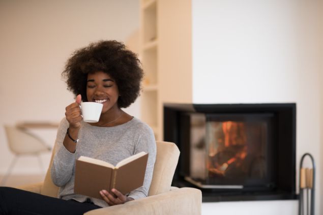 Imagem de uma pessoa do signo de gêmeos lendo um livro, com a tv ligada ao mesmo tempo, dispensando a atenção.