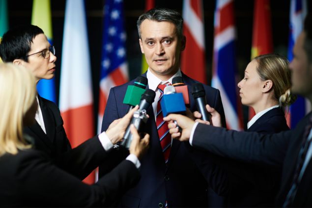 Imagem de um político dando uma entrevista a vários jornalistas.
