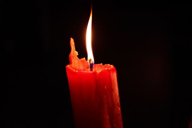 Imagem de fundo preto e em destaque uma vela vermelha usada para oferenda em ritual da Quimbanda.