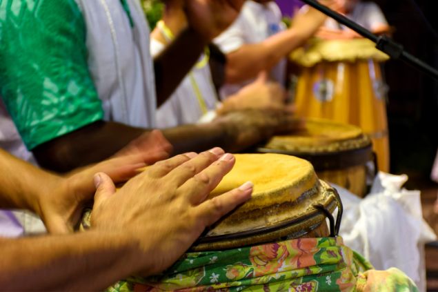 Imagem de pessoas tocando atabaque em um terreiro de Umbanda em um ritual para os boiadeiros.