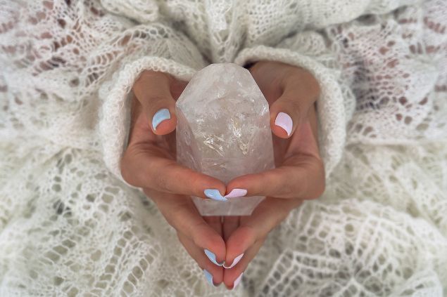Imagem das mãos de uma mulher segurando um cristal branco para a sua proteção espiritual, como forma de descarrego.
