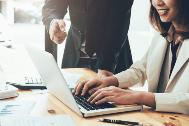 Homem em posição de chefe supervisionando o trabalho de sua funcionária. 