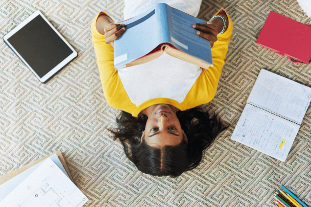 Menina lendo livro, focada nos estudos. 