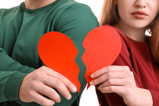 Casal jovem segurando corações partidos. Conceito de fim de relacionamento. 