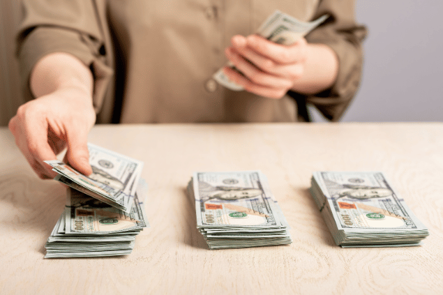 Pessoa distribuindo dinheiro em uma mesa, se planejando financeiramente. 